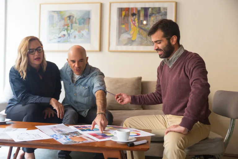 Interior designer explaining a detailed project quotation with budget estimates, material samples, and design plans during a client meeting